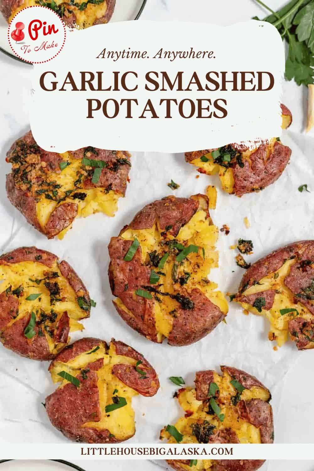 A tray of garlic smashed potatoes garnished with herbs, arranged on a sheet of parchment paper. The text at the top reads, "Anytime. Anywhere. GARLIC SMASHED POTATOES.