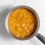 A pot with bubbling caramel on a marble countertop.