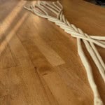 Twisted ropes of white dough are laid out on a wooden surface, partially overlapping each other in a loose braid pattern.