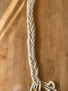 A braided dough strand rests on a wooden surface.