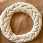 Braided dough shaped into a circular wreath on parchment paper.