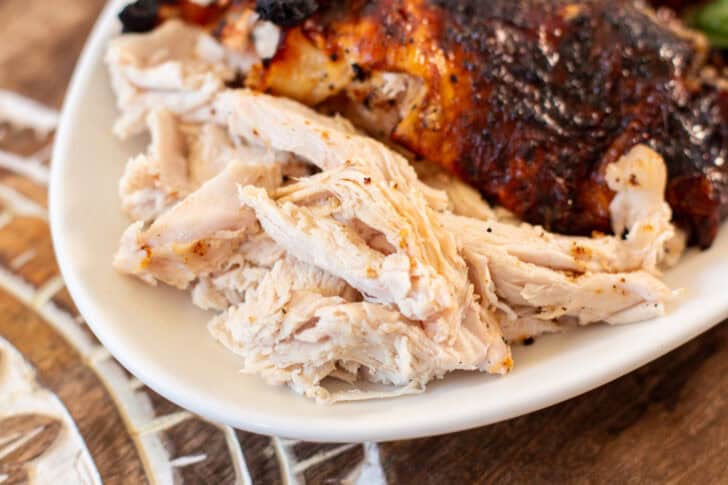 Shredded roasted chicken on a white plate with crispy skin in the background offers a delightful twist on traditional turkey recipes.
