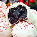 Close-up of white chocolate truffles with crushed peppermint on top, one cut open to reveal a rich, dark chocolate center.
