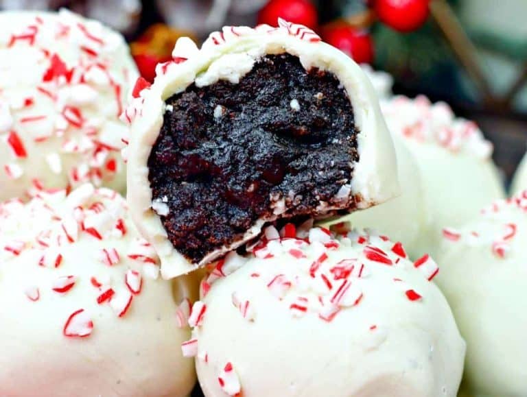 Close-up of white chocolate truffles with crushed peppermint on top, one cut open to reveal a rich, dark chocolate center.