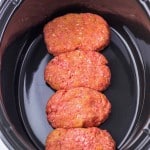 Four raw meatloaf portions in an oval slow cooker.