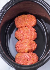Four raw meatloaf portions in an oval slow cooker.