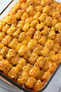 A baking dish filled with a baked casserole topped with golden-brown tater tots and melted cheese.