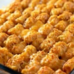 A glass baking dish filled with a golden-brown tater tot casserole, topped with melted cheese.