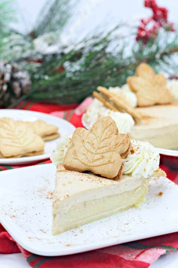 Slice of a pie garnished with leaf-shaped cookies and whipped cream on a plate, with a festive background.