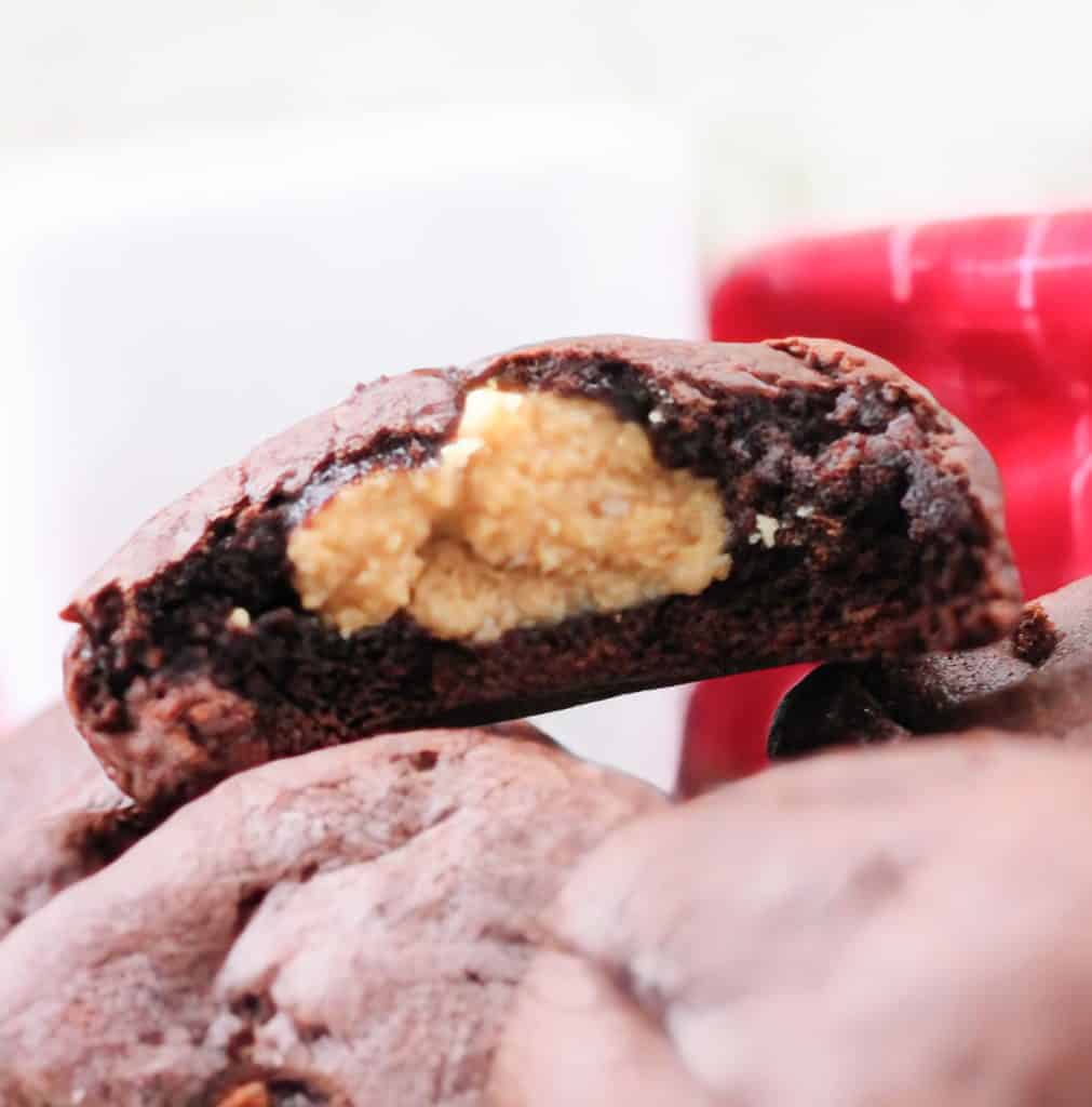 Close-up of a chocolate cookie with a peanut butter filling, shown on a red and white background.