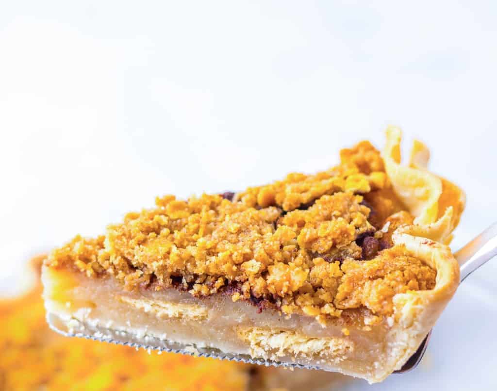 A slice of pie, one of the iconic pie favorites, with a crumbly topping rests invitingly on a fork against a delicately blurred background.