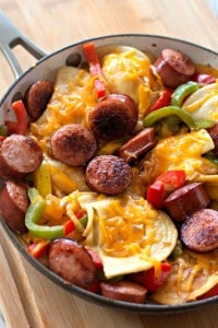 Kielbasa skillet featuring sliced sausage, bell peppers, onions, potatoes, and melted cheese.