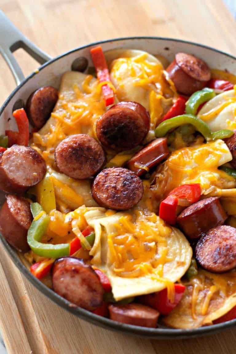 Kielbasa skillet featuring sliced sausage, bell peppers, onions, potatoes, and melted cheese.