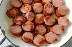 Sliced sausages sizzle in the Kielbasa skillet, with some pieces browned to perfection.