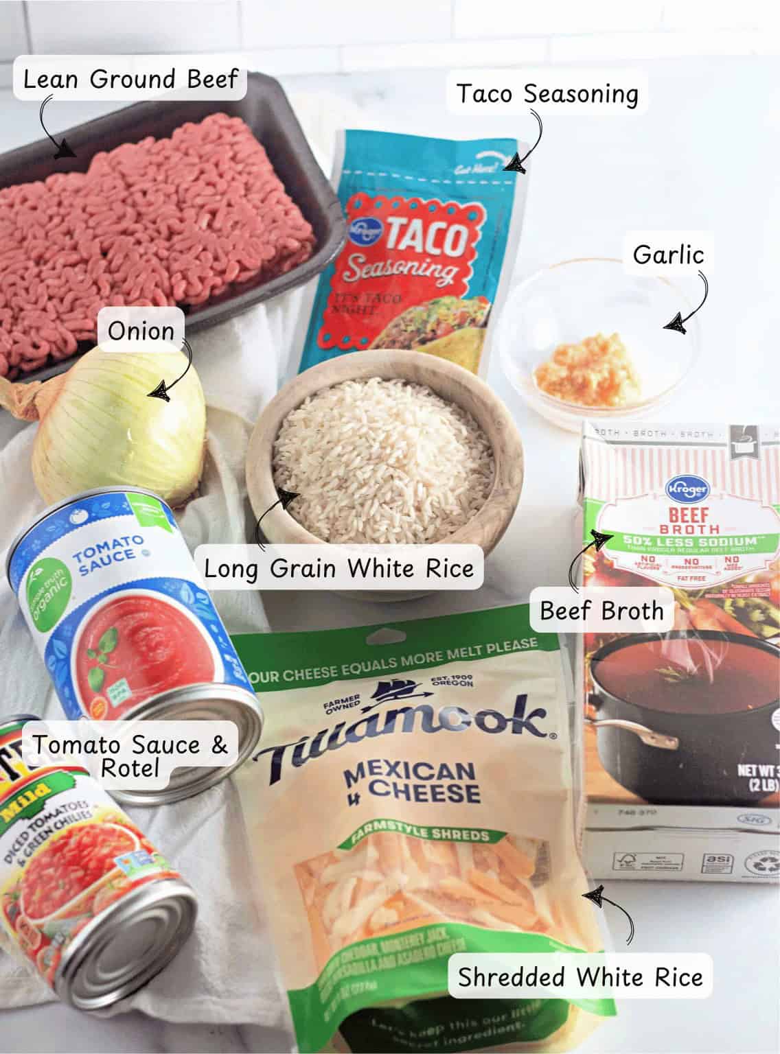 Ingredients for a flavorful taco rice skillet are displayed, featuring ground beef, taco seasoning, onion, garlic, rice, beef broth, tomato sauce, Rotel, and shredded cheese.