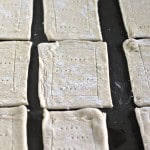 Rectangular pieces of raw pastry dough with fork pricks, perfect for making delicious blueberry Danishes, are arranged on a baking sheet.