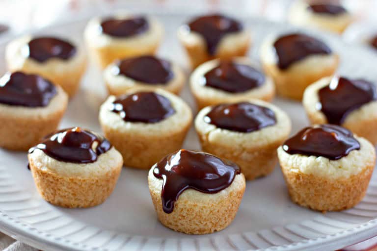 A plate of mini Boston Cream Pie Cookies topped with chocolate glaze, elegantly arranged in rows on a white platter.