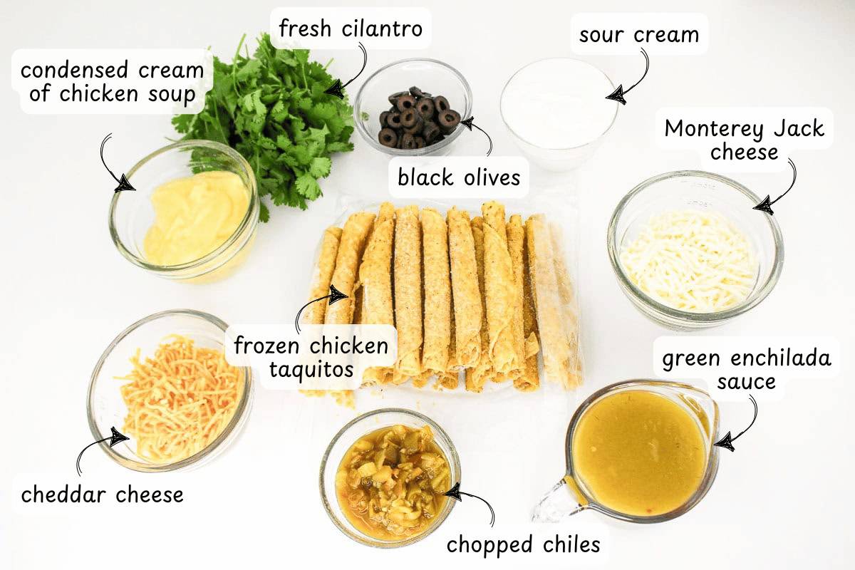 Ingredients for a Chicken Taquito Casserole are arranged on a table: fresh cilantro, sour cream, Monterey Jack cheese, frozen chicken taquitos, green enchilada sauce, chopped chiles, cheddar cheese, black olives, and condensed cream of chicken soup.