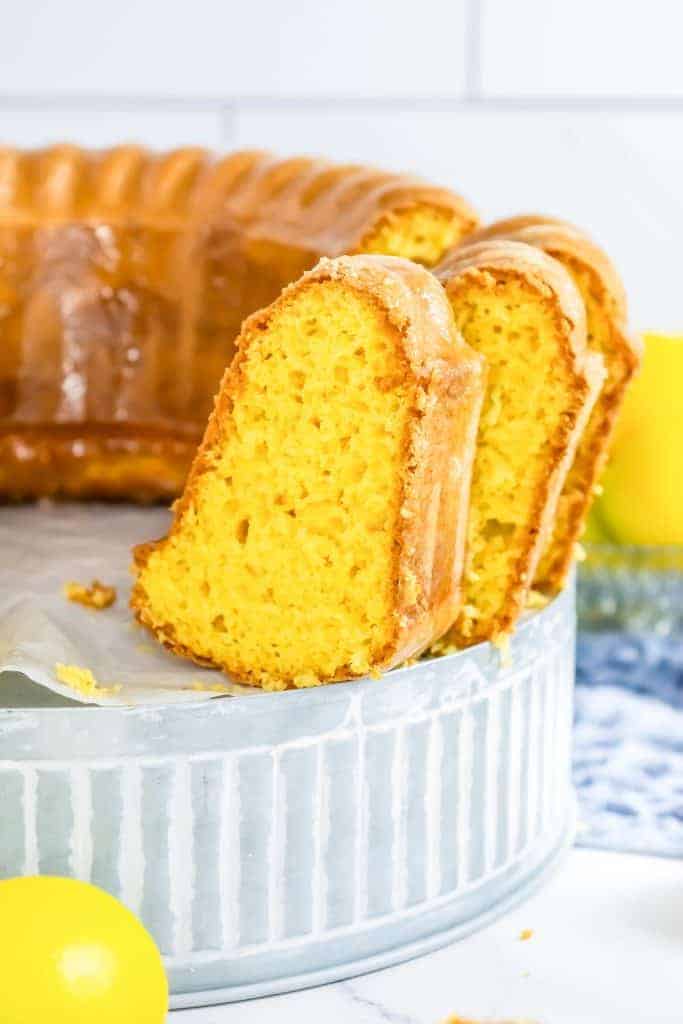 Two slices of lemon bundt cake with a glazed topping rest on a metal tray.