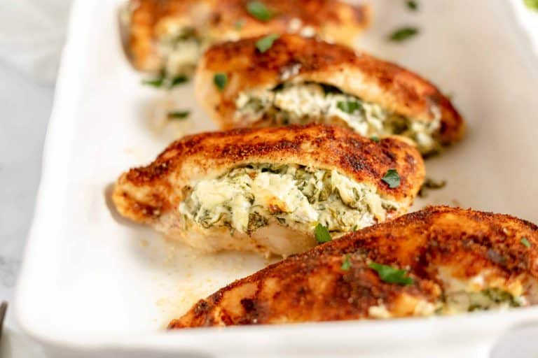 Quick Chicken: Succulent chicken breasts swiftly prepared, stuffed with a creamy spinach and cheese filling, and garnished with chopped herbs, served elegantly in a white dish.