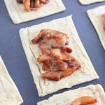 Rectangular pastry sheets topped with a spiced apple filling are arranged on a baking tray to create a delightful apple crumb Danish.