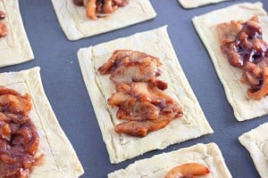 Rectangular pastry sheets topped with a spiced apple filling are arranged on a baking tray to create a delightful apple crumb Danish.