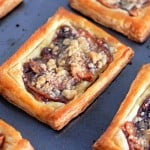 Rectangular apple crumb Danish pastries with a flaky crust, topped with apple slices and a crumbly streusel, are arranged on a baking tray.