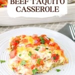 A serving of beef taquito casserole topped with diced tomatoes, melted cheese, and chopped herbs on a white plate, with a fork beside it.