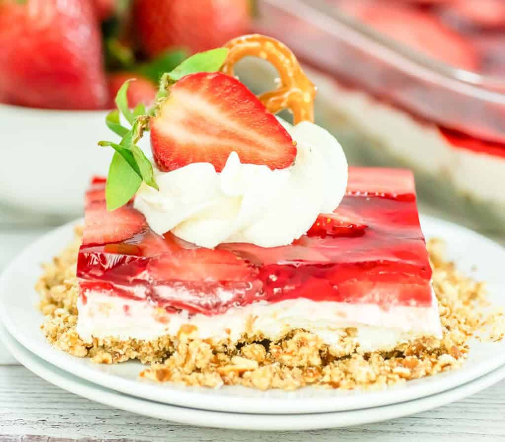 A jello dessert with berries and white layer on a crumb base. 