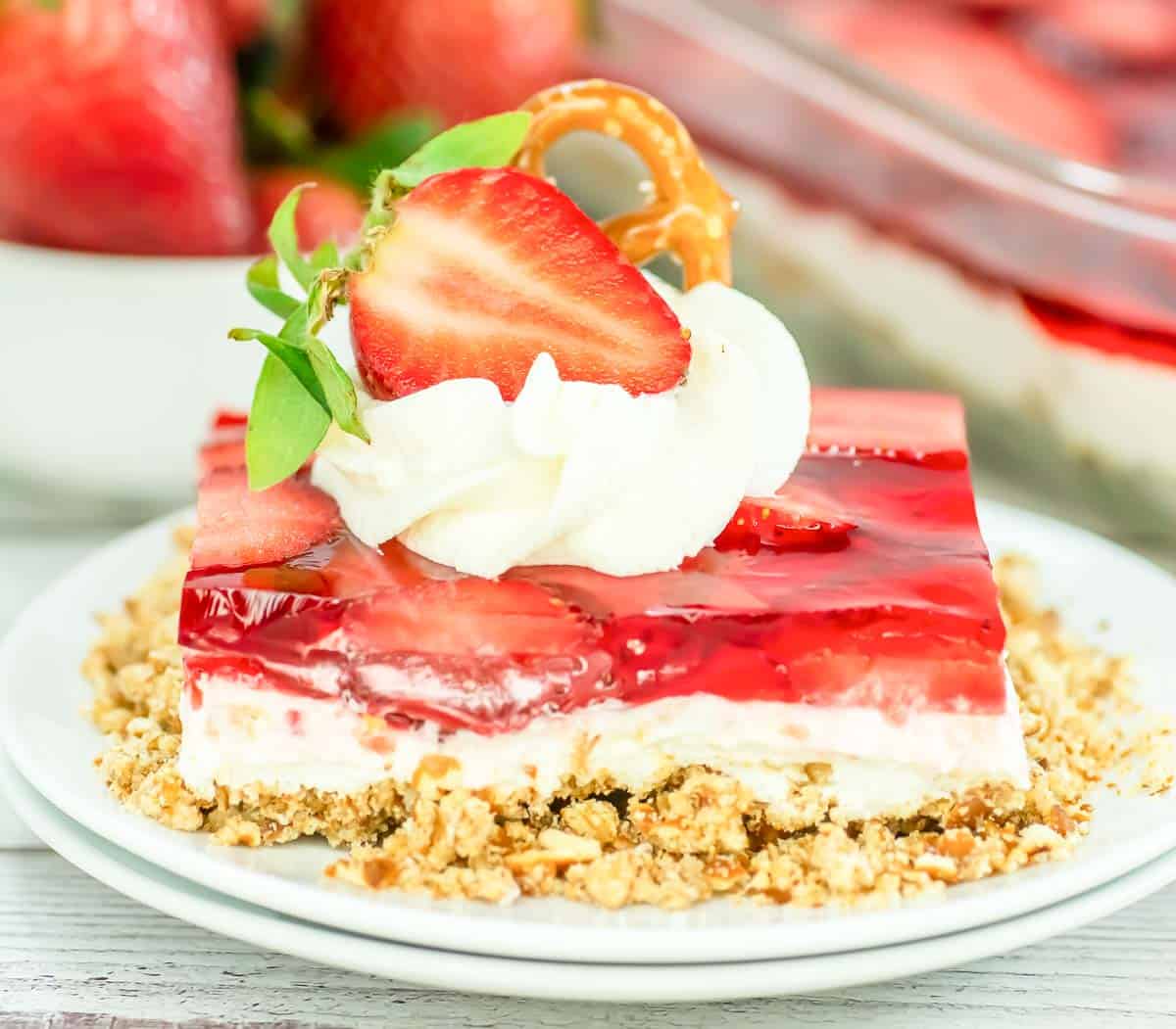 A jello dessert with berries and white layer on a crumb base.