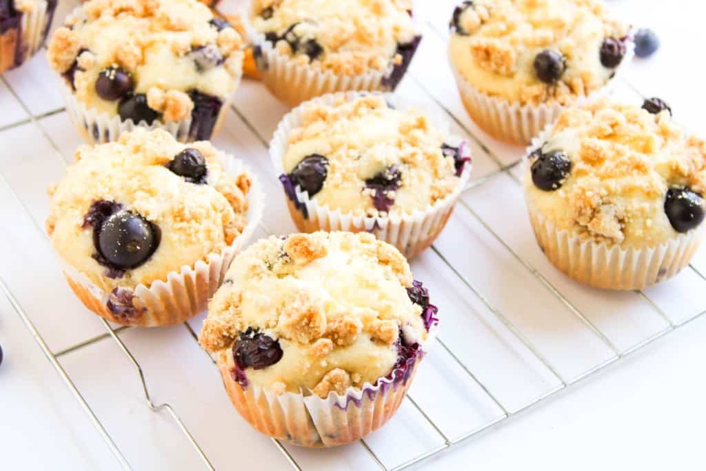 Blueberry Cheesecake Muffins with a crumb topping cooling on a wire rack.