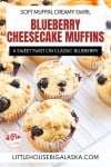 Several Blueberry Cheesecake Muffins with crumb topping sit on a cooling rack, with a text overlay promoting the recipe from littlehousebigalaska.com.