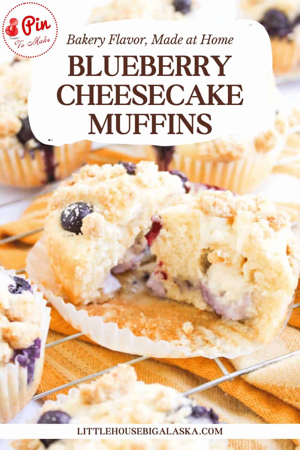 Blueberry Cheesecake Muffins with crumb topping displayed on a tray, one muffin cut open to reveal the creamy cheesecake filling and juicy blueberries inside.