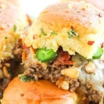 Close-up of Cowboy Sliders featuring ground beef, melted cheese, sliced jalape&ntilde;os, bacon, and herbs on a golden bun.