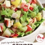 A bowl of Grinder Chopped Salad with lettuce, diced meats, cheese, tomatoes, and peppers is pictured, with text overlay reading "Grinder Chopped Salad" and a website link at the bottom.