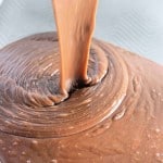 Chocolate cake batter being poured into a baking pan.