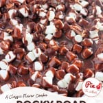 Close-up of a rocky road sheet cake topped with chocolate glaze, mini marshmallows, and chopped pecans. Text overlay reads "Rocky Road Sheet Cake.