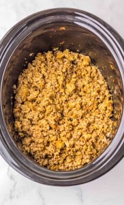 Cooked seasoned ground beef in a slow cooker, viewed from above on a marble countertop.