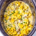 Cheese tortellini, ground sausage, and creamy sauce cooked together in a slow cooker, topped with chopped parsley.