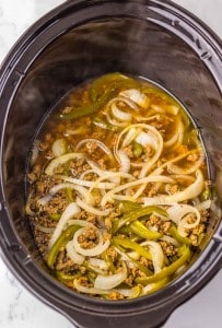 Ground meat, sliced onions, and green bell peppers cooked together in a slow cooker with broth or sauce.