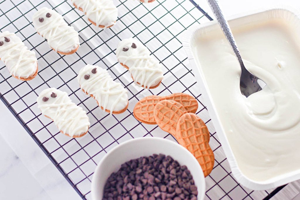 Nutter Butter cookies decorated as ghosts and mummies with white chocolate and chocolate chip eyes.