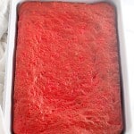 A rectangular white baking dish filled with a baked, evenly textured, bright pink cake.