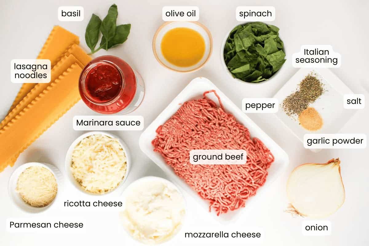 Sheet pan Lasagna ingredients laid out, including lasagna noodles, marinara sauce, ricotta, mozzarella, Parmesan, ground beef, onion, spinach, basil, olive oil, and spices. Perfect for an easy sheet pan meal.