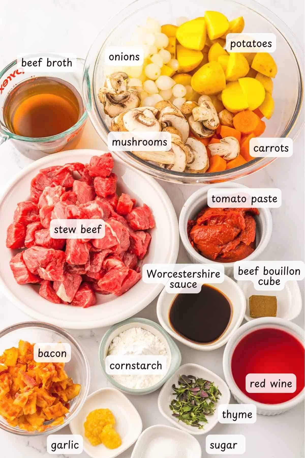 Various labeled ingredients for Slow Cooker Beef Bourguignon are arranged in bowls and plates, including beef, vegetables, liquids, seasonings, and bacon.