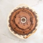 A freshly baked German Chocolate Bundt Cake sits in a fluted ceramic pan on a light-colored marble surface.