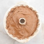 A German Chocolate Bundt Cake batter fills a bundt pan, shown from above on a light marble surface.