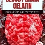 A molded red gelatin dessert shaped like a brain, placed on a dark leafy background, with promotional text for a Halloween-themed recipe.