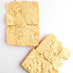 Two slices of crumbly bread are placed on a white surface, with visible crumbs scattered around them.