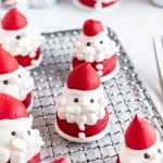 Several Santa Claus-shaped meringue cookies with red hats and white beards are arranged on a cooling rack.