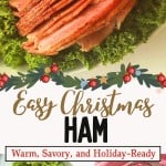 A glazed, sliced ham is served on a bed of leafy greens, accompanied by cranberry sauce and holiday-themed decor. Text reads: "Easy Baked Ham with Cranberry Pineapple Glaze—Warm, Savory, and Holiday-Ready.